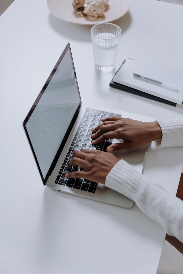 story-02 A woman typing on a laptop at a minimalist, modern home office desk, showcasing productivity.