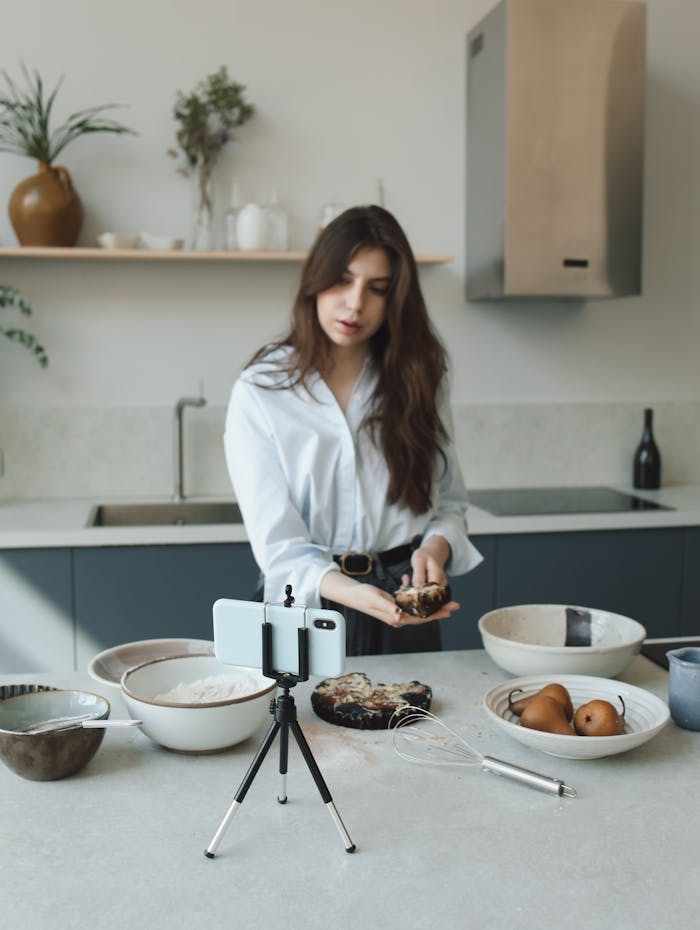 services-01 Woman creating a cooking blog video in a modern kitchen with phone on tripod.